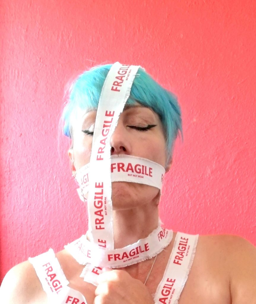 artist bound in tape reading Fragile but not weak